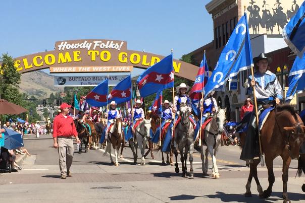 Riders bearing flags parade on horseback up Washington Avenue