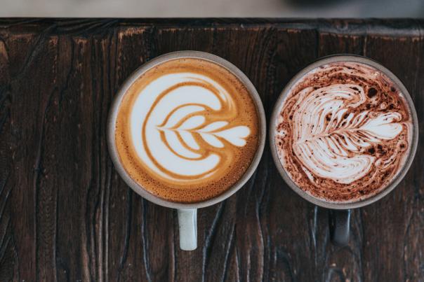 Two coffee mugs with decorative foam on a table