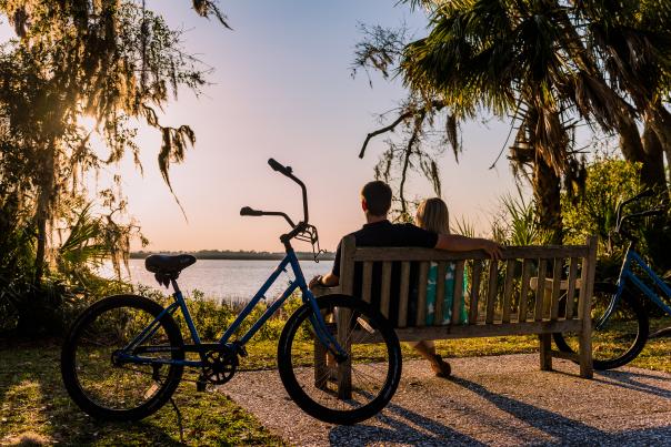 A couple takes a break from their bike ride to enjoy the sunset along the bike trail on Jekyll Island, Georgia