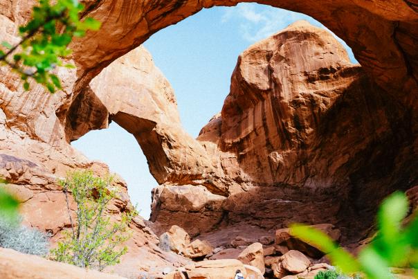 A woman walking under Double Arch at Arches National Park near Moab.