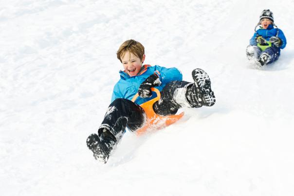 Two Kids Sledding in the Snow