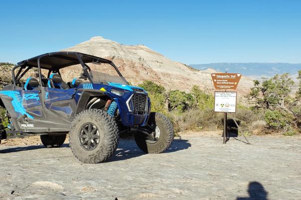 Picture of Blue RZR in Desert Parked in Front of Sign