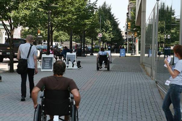 Man on wheelchair travelling on sidewalk in downtown Grand Rapids