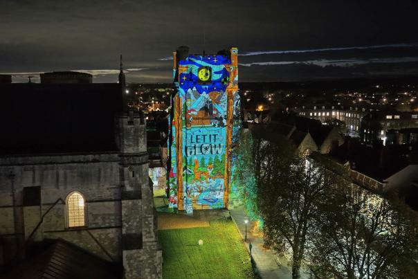 An image showing the bell tower of Chichester Cathedral lit with Christmas images for let it glow