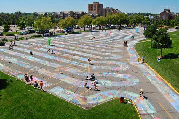 People participating in Chalk A Lot at a UNC parking lot to set a Guinness World Record for the longest chalk art.