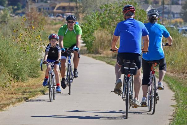 Father and son bike the Poudre Trail in Greeley, Colorado, passing other bikers