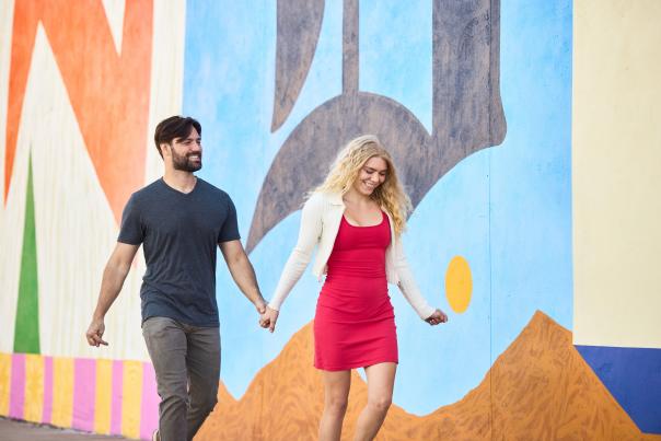 Couple on a date in Greeley, CO walking in front of the Wonder Wall