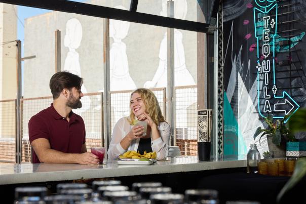 Couple eating with drinks at the bar smiling