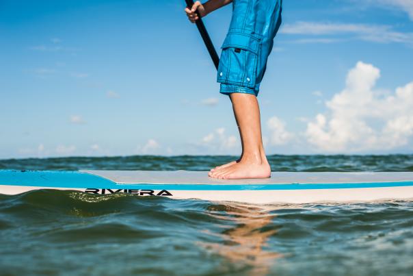 A Young boy stands on a paddleboard in St. Joseph Bay
