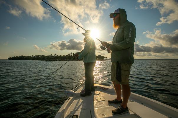 Two men fish from a boat as the sun rises over St. Joseph Bay