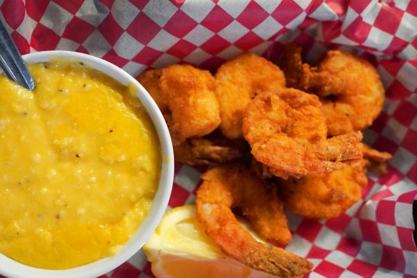 a plate of fried shrimp and cheese grits on a red and white checkered paper
