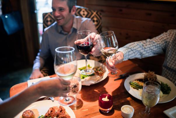 A group of people at dinner raising their wine glasses for a toast.