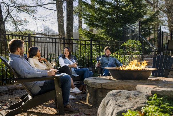 Two men and two women sitting around a fire pit.