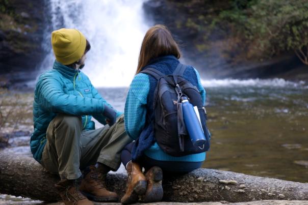 Couple sitting next to a waterfall.