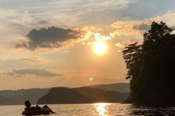 A man inner-tubing on Raystown Lake near sunset