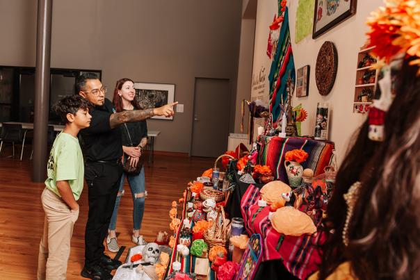 A family looking at an ofrenda for Dia De Los Muertos Mexican holiday in the Fort Wayne Museum of Art