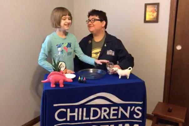 Mother and Daughter Working on science experiments at a table with banner reading "The Children's Museum of Indianapolis"