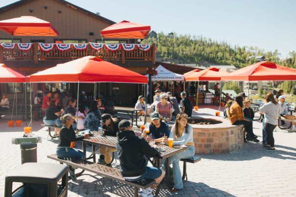 A crowd of people dressed for warm weather gathers on the patio