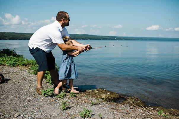 father and daughter with fishing pole at lake