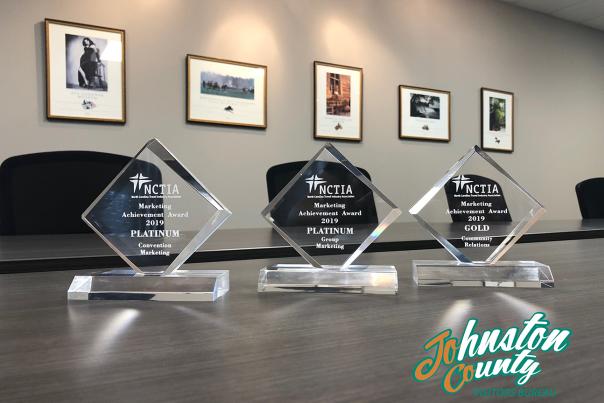 Three clear awards sit in a row on a conference table.