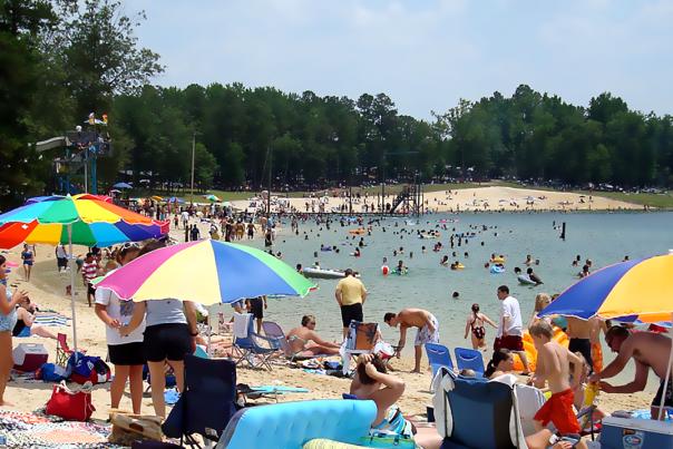 People in bathing suits set up on the sand at Tucker Lake in Benson, NC.