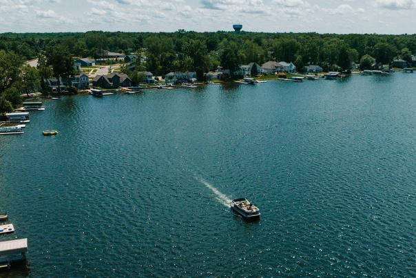 A white boat moves across  Gourdneck Lake, a vibrant blue lake in Portage, MI.