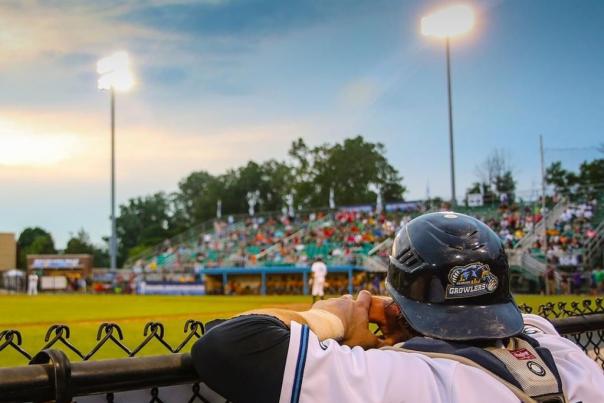 A baseball player leans on the fence