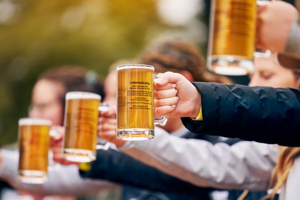 a group of hands holding out mugs of beer