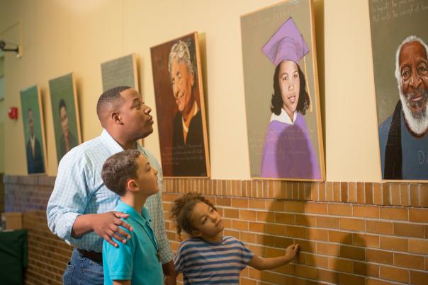 A father and two children admiring portraits at the Brown V Board Museum.