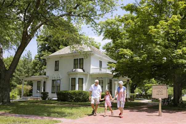 Grandparents and grandchild walk through Eisenhower Presidential Library Statue