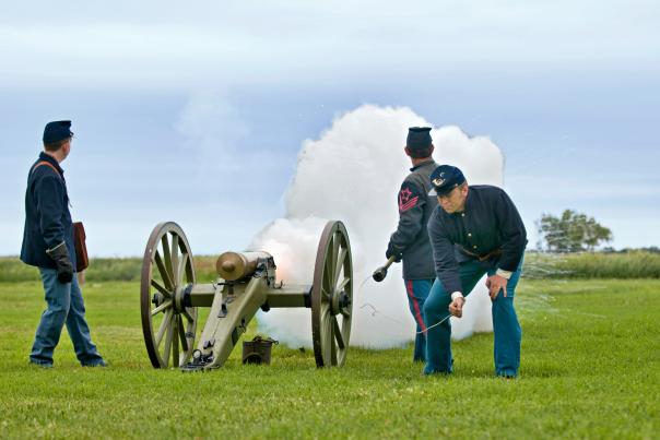 Two men fire a cannon at Fort Larned
