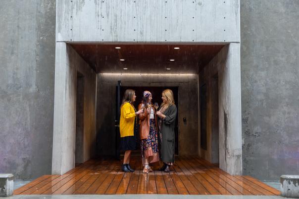 Three_Women_Toasting_with_Wine_Glasses_Under_Entranceway_to_Wine_Caves