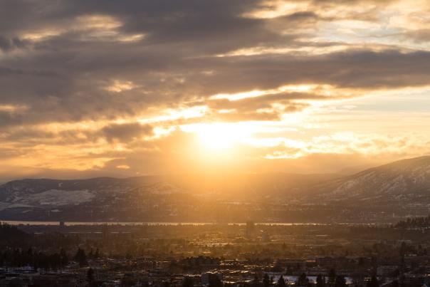 Sun setting behind snow-covered mountains in Kelowna