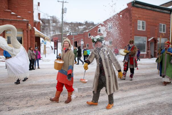 Person dressed as Heikki Lunta throws snow during parade