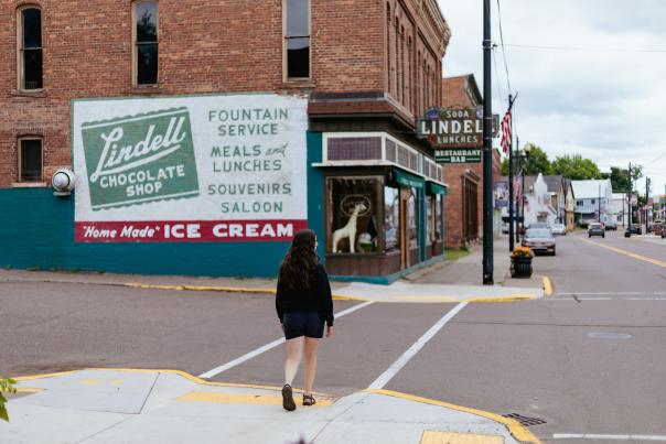 a person crosses a street towards a historic brick building