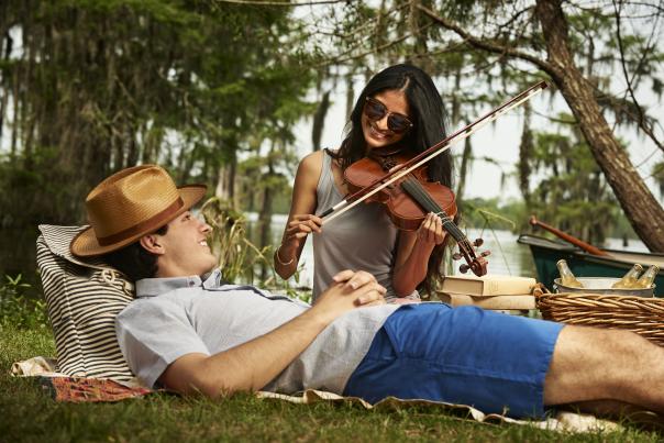 Woman playing the fiddle to reclined partner at Lake Martin.