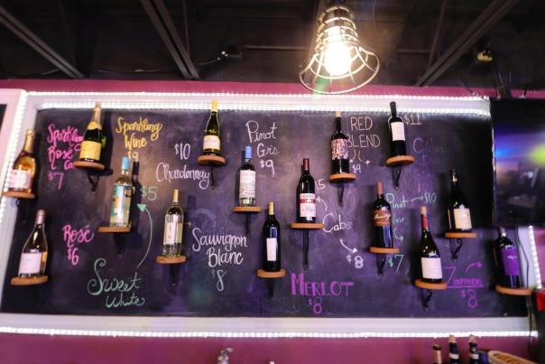 various wines are displayed on the wall at The Wine Store and labeled