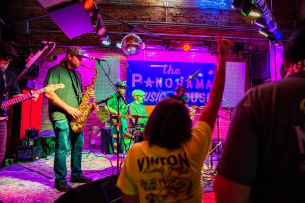 jazz musicians play onstage with saxophone, guitar, keyboard, and drums at panorama music house