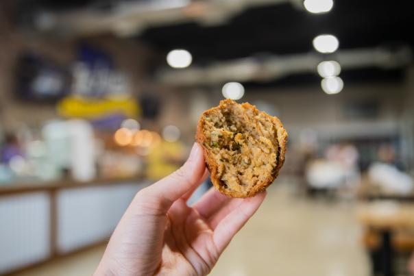 half eaten boudin ball filled with rice, meat, herbs, and spices from in-laws-moss bluff