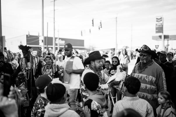 black and white photo of a crowd gathered with musical instruments and dressed in mardi gras attire at the Iowa Chicken Run
