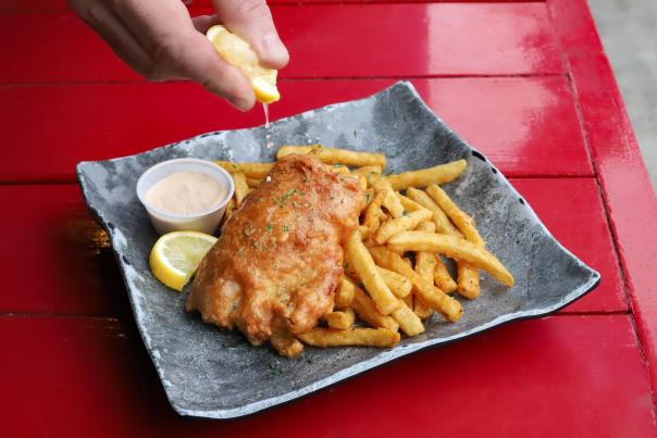 crispy fried fish and seasoned fries served with sauce and lemon wedges