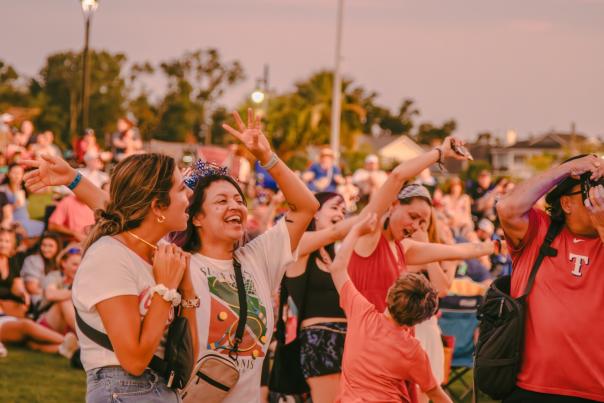 women dressed in red, white, and blue dance in the crowd during a concert