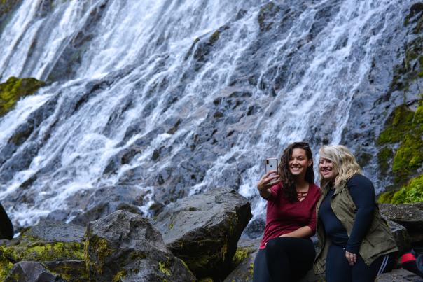 Two women take a selfie in front of Diamond Creek Falls.