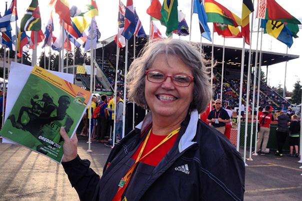 Juanita holding program in front of country flags at IAAF Juniors