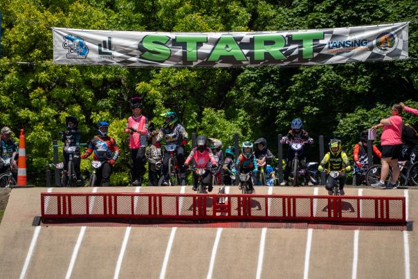 A group of BMX athletes lining up at the start, preparing for their run during the BMX State Race.