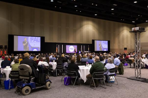 A group of tables and large screens at the Lansing Center during a conference