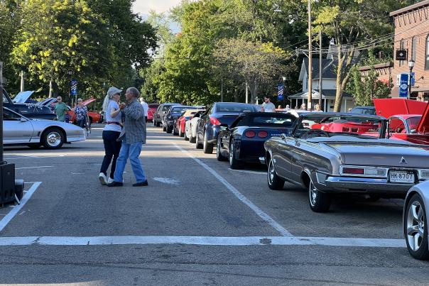People dancing in the streets next to classic cars