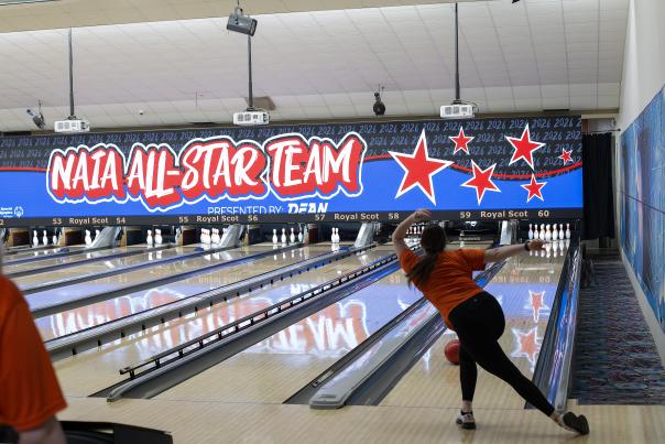 Line of bowling lanes with one bowler throwing the ball
