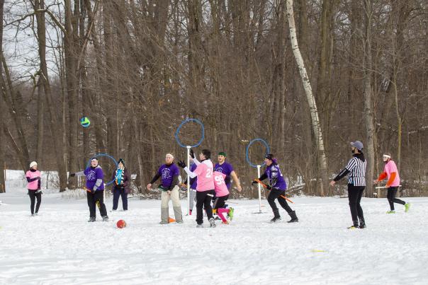 Athletes playing quadball in a wooded snow-covered clearing