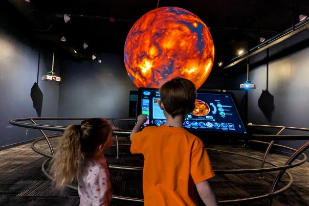 Two kids looking at a monitor of the sun in the sphere room at the MSU Museum